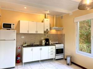 a kitchen with white cabinets and a white refrigerator at Maitenes Del Percy in Trevelín