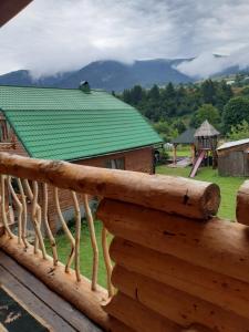 a wooden deck with a green roof on a house at Sadyba u Anastasijky in Synevyr