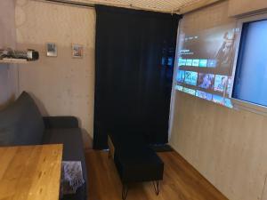 Cette chambre comprend un rideau noir, un canapé et un écran. dans l'établissement TINY HOUSE Cosy 1 - Angers Green Lodge, à Angers