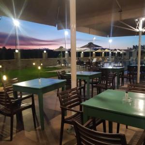 a restaurant with green tables and chairs with the sunset at Hotel Sias Resort in Agios Avgoustinos