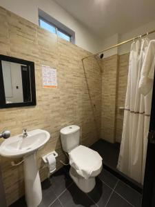 La salle de bains est pourvue de toilettes blanches et d'un lavabo. dans l'établissement ZUGI INN HOTEL, à Leticia