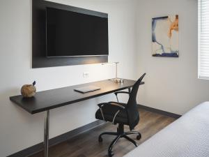 einen Schreibtisch mit Stuhl und einen TV an der Wand in der Unterkunft stayAPT Suites Greenville-Haywood Mall in Greenville