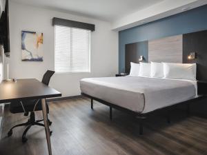 stayAPT Suites Greenville-Haywood Mall في غرينفيل: غرفة نوم بسرير ومكتب وطاولة