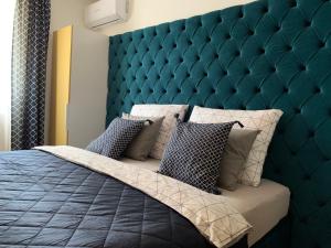 a bedroom with a large bed with a blue padded headboard at Hollik Apartmanház in Balatonfüred