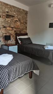a bedroom with two beds and a stone wall at “Sa Scala” Bed&Terrace in Baunei