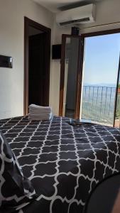 a bedroom with a black and white bed with a large window at “Sa Scala” Bed&Terrace in Baunei