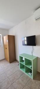 a room with a green cabinet and a television on a wall at Apartment Twins in Pag