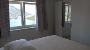 1 Schlafzimmer mit 2 Fenstern und Blick auf das Wasser in der Unterkunft APARTMAN KARLA in Lastovo