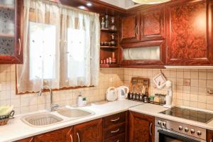 una cucina con armadi in legno, lavandino e finestra di Antonia House a Città di Skiathos Altre 111 foto
