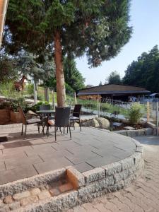 un patio con sedie, un tavolo e un albero di Ferienhaus auf dem Lusitanohof Jäger a Fürth