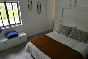 a white bedroom with a bed and a window at L'annexe des Cigales, à l'ombre des chênes lièges in Capbreton