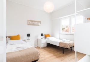 a white bedroom with two beds and a mirror at PAREDE APARTMENT 2 in Cascais