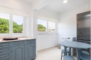 a kitchen with blue cabinets and a table and two windows at PAREDE APARTMENT 2 in Cascais +3 photos