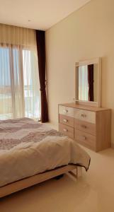 a bedroom with a bed and a dresser with a mirror at HAWANA villa 010 هوانا فيللا in Salalah