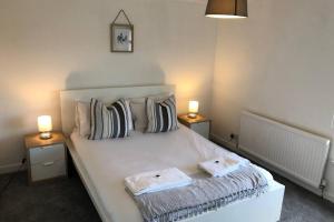 a bedroom with a white bed with two towels on it at Clives Place - End of terrace two bedroom cottage in Cwm-brân