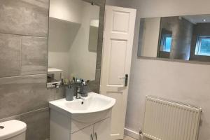 a bathroom with a sink and a toilet and a mirror at Clives Place - End of terrace two bedroom cottage in Cwm-brân