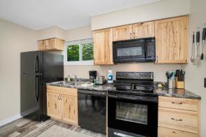 una cocina con electrodomésticos negros y armarios de madera en Crystal Mountain Charm, en Thompsonville