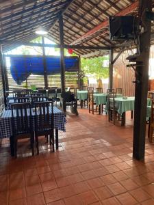 a restaurant with green tables and chairs and a roof at Pousada Encantos da Amazônia in Alter do Chao