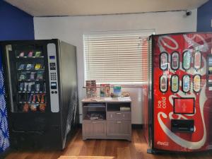 - un réfrigérateur coca cola à côté d'une machine à soda dans l'établissement Exchange Club Motel, à Beatty