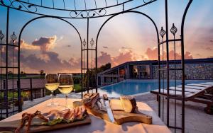 タルクイーニアにあるVilla Hotel Valle Del Marta Resortのプール付きのヴィラで、ワイン2杯を用意しています。