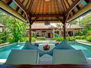 eine Terrasse mit Stühlen und einem Pool in der Unterkunft Villa Kedidi in Canggu