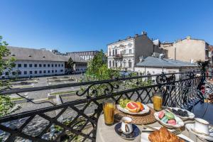 HOLT Old Town Suites with Balcony في بوخارست: طاولة مع طعام ومشروبات على شرفة