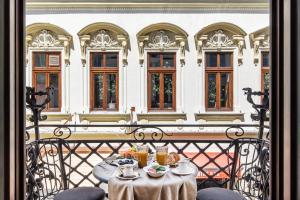 HOLT Old Town Suites with Balcony في بوخارست: طاولة مع طعام ومشروبات على شرفة