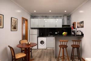 eine Küche mit weißen Schränken und einem Tisch und Stühlen in der Unterkunft Vila do Largo by Homie in São Vicente + 15 Fotos