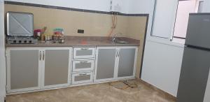 una cocina con armarios blancos y fregadero en Superbe Appartement bouki, en Alhucemas