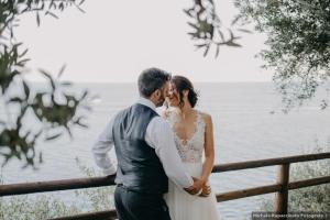 a bride and groom standing next to a fence at Hotel Costa Diva in Praiano