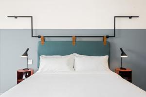 ロサンゼルスにあるThe Metric - Los Angeles Downtownの大きな白いベッドと2つのランプのある寝室