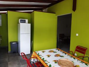 Cette chambre comprend une table, un réfrigérateur et des murs verts. dans l'établissement La Poulette amazonienne, à La Mauny