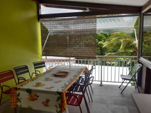 una mesa y sillas en una habitación con balcón en La Poulette amazonienne en La Mauny