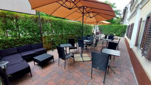 d'une terrasse avec des tables, des chaises et un parasol. dans l'établissement Vén Diófa De Lux Panzió, à Szeged