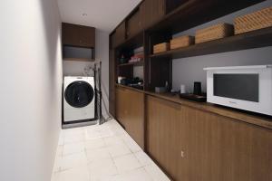 eine Waschküche mit einer Waschmaschine, einem Trockner und einem TV in der Unterkunft abrAsus hotel Fuji in Narusawa
