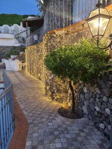 eine Steinmauer mit einem Baum und einem Straßenlicht in der Unterkunft L'Incanto Suites Ischia in Ischia