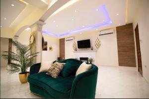 ein Wohnzimmer mit einem grünen Sofa und einem TV in der Unterkunft شاليه اوتار Strings Chalet in Riad