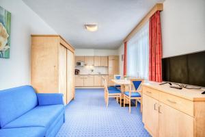 a living room with a blue couch and a kitchen at Appartementhaus Sonneck in Imst