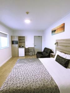 a hotel room with a large bed and a chair at Childers Oasis Motel in Childers +33 photos
