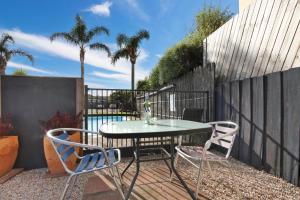 a patio with a table and two chairs and a fence at Cunningham Shore Motel in Lakes Entrance