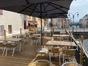 un patio al aire libre con mesas, sillas y una sombrilla en Le Miredames Hôtel-Bar en Castres