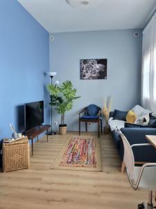 a blue living room with a couch and a tv at L'idéal Mairie de Montreuil in Montreuil
