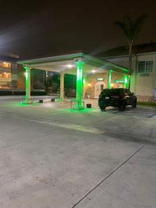 ein Auto parkt auf einem Parkplatz mit grüner Beleuchtung in der Unterkunft Mid City Inn & Suites Pico Rivera in Pico Rivera