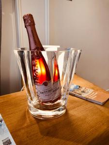 a bottle of alcohol in a glass vase on a table at Hôtel Porte Mars Reims Gare Centre Arena in Reims