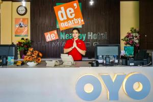 a person standing behind a desk with a sign at OYO 770 De Nearby Hotel in Manado