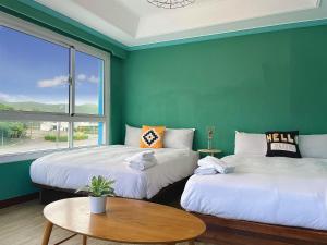 two beds in a room with a table and a window at 海中天旅店 Sea Of The World B&B in Kenting