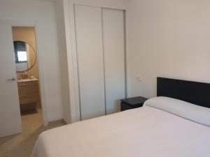 ガンディアにあるPlaya Gandía Residencial Álamoの白いベッドと鏡のある寝室 +15枚の写真