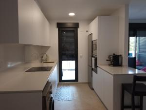 ガンディアにあるPlaya Gandía Residencial Álamoのキッチン(白いカウンター付)、窓付きのドア