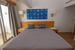 a bedroom with a bed with a blue painting on the wall at Tylos Beach Hotel in Kato Pyrgos