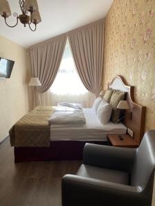 a bedroom with a bed and a chair and a window at Residence Hotel & Spa in Repino